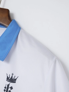 Détail d'un polo blanc en maille avec col bleu et logo couronne imprimé