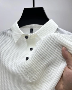Gros plan d'un polo blanc en soie glacée avec texture gaufrée et boutons noirs