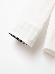 Close-up of white dress shirt cuff with stylish black and white gingham inner lining