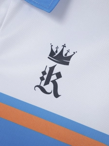 Gros plan du polo en maille piquée blanche avec rayures bleues et logo couronne