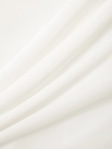Close-up of white plain weave fabric showing the fine texture and natural drape of the shirt
