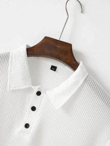 Détail d'un polo blanc en soie glacée avec trois boutons noirs et une texture gaufrée