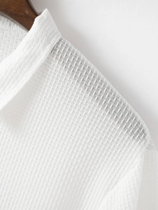 Vue macro du polo blanc montrant la texture gaufrée respirante et les coutures précises