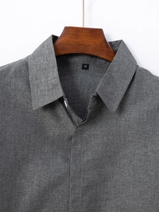 Dettaglio del classico colletto a punta e del tessuto grigio scuro testurizzato della camicia