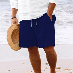 Detalle de los pantalones cortos de lino a rayas azul marino con cordón en la playa