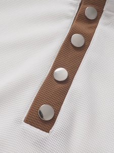 Detail of white waffle knit polo shirt with brown placket and silver snap buttons