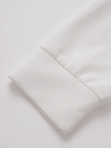 Close-up of white waffle texture fabric and ribbed cuffs on men's long sleeve polo shirt