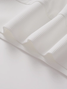 Detailed macro view of white waffle knit fabric texture on men's polo shirt