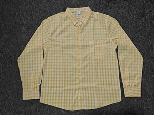 Detailed view of yellow gingham plaid men's shirt with front pocket on gray surface