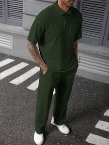 Detailed view of dark green textured knit polo shirt and trousers on male model