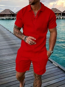 Detail of red men's polo set showing 3D textured knit fabric on a coastal boardwalk