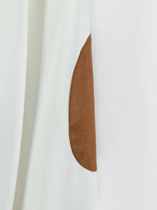 Detail of white men's jacket featuring brown faux suede oval elbow patch with stitching
