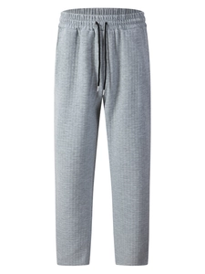 Detail of light gray men's joggers with square quilted texture and drawstring waistband