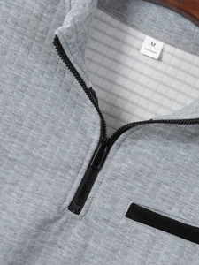 Detailed view of light grey waffle texture fabric and black zipper on men's polo shirt