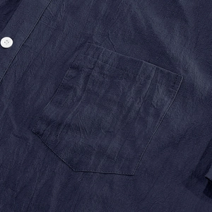Detail van marineblauw linnen overhemd met borstzakje en witte knoopafwerking