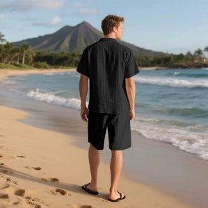 Rückansicht von Herren-Leinen-Set aus schwarzem Kurzarmhemd und Shorts am Tropenstrand