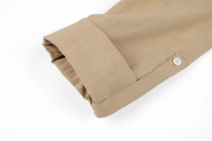 Detail of rolled cuff with single white button on khaki linen texture shirt sleeve