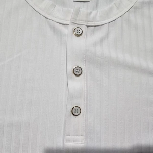Detail of white ribbed knit fabric on Henley shirt featuring three elegant buttons