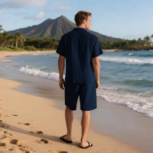 Detail von dunkelblauem Leinen-Set aus Hemd und Shorts vor tropischem Strand
