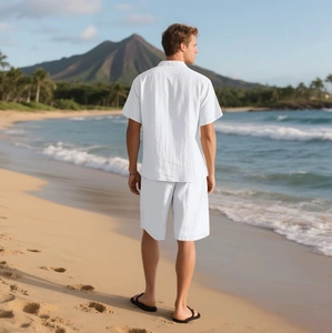 Detailansicht von weißem Leinen-Set aus Hemd und Shorts am sonnigen Strandhintergrund
