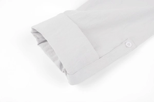 Detail of light grey linen shirt sleeve featuring roll-tab button and textured fabric