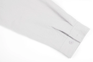 Detailed close-up of light grey linen shirt cuff with button and natural fabric texture