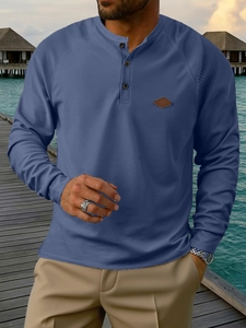 Detail view of men's blue waffle knit Henley shirt showing texture and leather patch