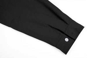 Detailed macro view of black linen shirt cuff with white button and refined stitching