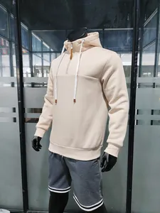 Dettaglio felpa beige con mezza zip, cordini bianchi e finiture in pelle sulle punte