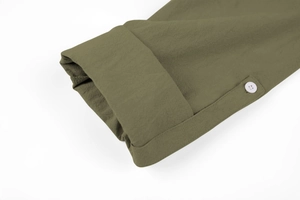 Detail of roll-up sleeve on olive green linen Henley shirt with white button and stitching
