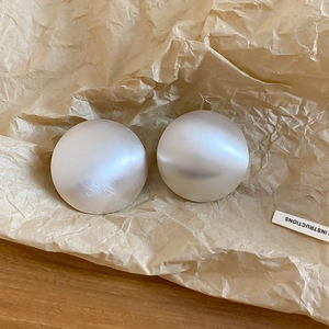 Gros plan de boucles d'oreilles dôme en argent brossé sur papier kraft, bijou élégant.