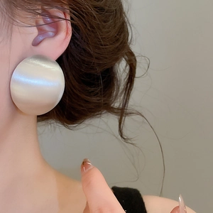 Gros plan détaillé montrant la texture de grandes boucles d'oreilles géométriques