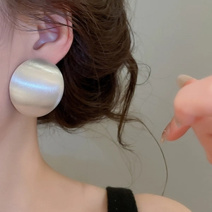 Détail rapproché de boucles d'oreilles rondes en métal argenté brossé pour femmes