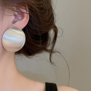 Détail de grandes boucles d'oreilles ovales géométriques en argent brossé