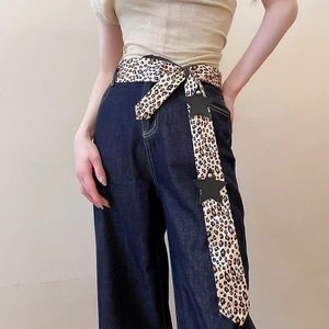 Close-up detail of leopard print Y2K belt with star accents worn on dark denim jeans