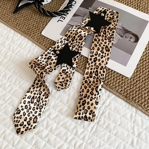 Close-up detail of Y2K leopard print satin belt with black leather star accents