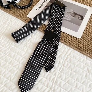 Close-up of Y2K style black polka dot silk belt with leather pentagram stars on a bed