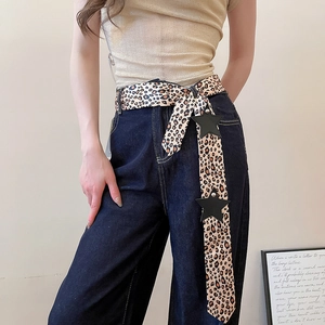 Close-up of Y2K spicy girl leopard print belt with black star charms on dark denim jeans.