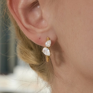 Gros plan d'élégantes boucles d'oreilles en acier doré avec zircons en forme de poire