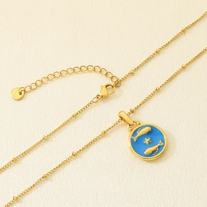 Primer plano detallado de un colgante de Piscis en esmalte azul con cadena de acero dorado.