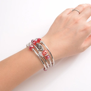 Detailed view of a multi-layer silver wrap bracelet with red crystal beads worn on a wrist