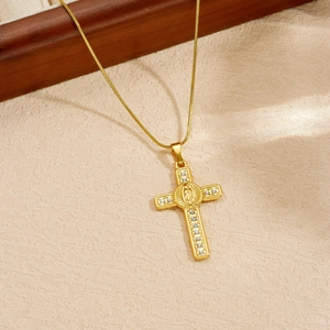 Primo piano della collana con ciondolo a croce placcata oro con pietre e figura.