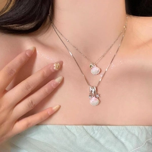 Dettaglio della collana a due strati in acciaio inox con ciondoli a conchiglia rosa.
