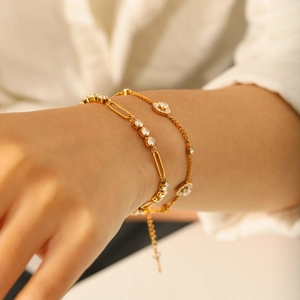 Elegante goudvergulde titaniumstalen armbanden met heldere kristallen om een vrouwenpols.