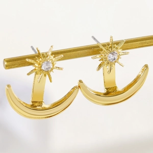 Close-up detail of gold-toned celestial star and moon stud earrings with rhinestone