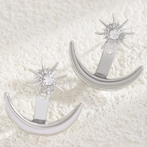 Macro detail of silver sun and moon ear jacket earrings with sparkling crystal centers