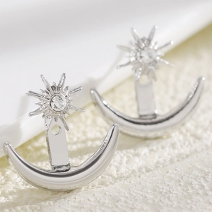 Close-up of silver star and moon earrings with sparkling sun stud and crescent charm.