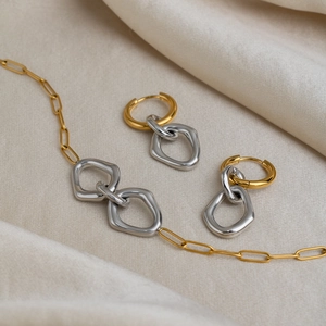 Macro view of minimalist two-tone stainless steel link necklace and hoop earrings set