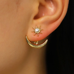 Macro view of gold sun and moon stud earring featuring a sparkling crystal stone