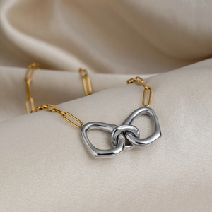 Close-up of minimalist two-tone interlocking ring pendant on a gold paperclip chain